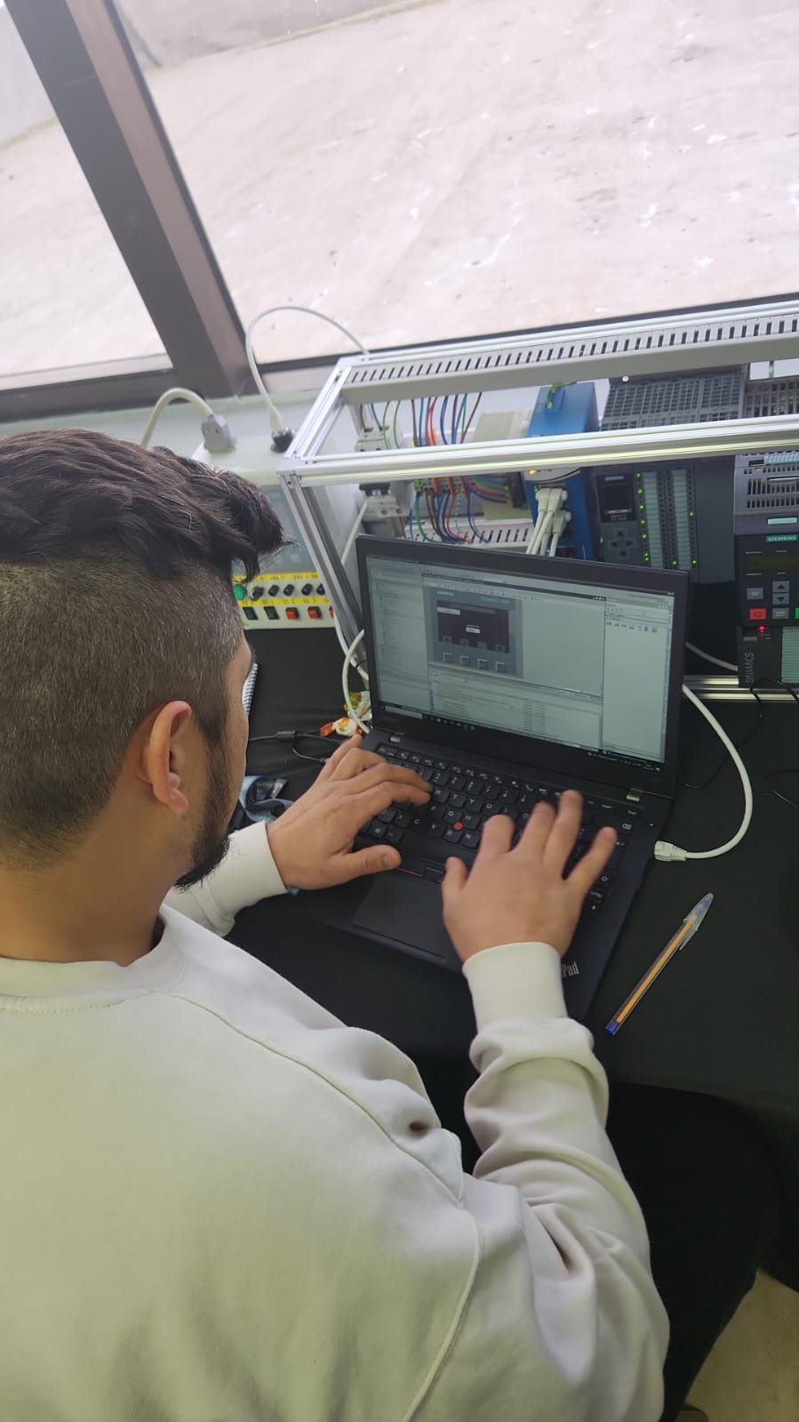 Dos participantes trabajando sobre el entrenador con el PLC Siemens montado en riel